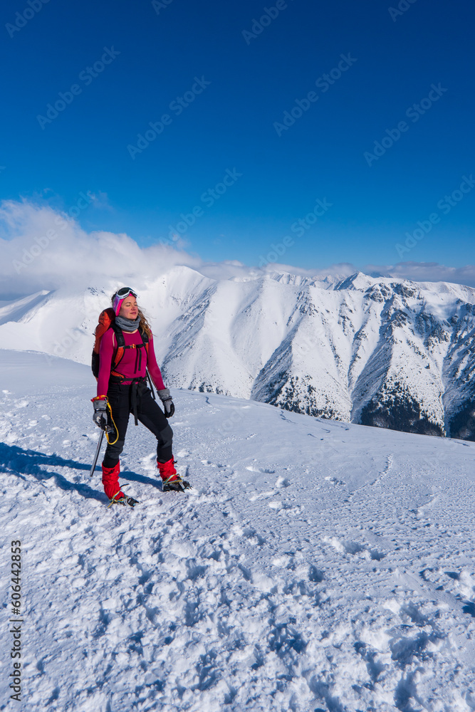 Happy woman relaxing on the top of mountain under blue sky with sunlight at sunny winter day, travel vacation, landscape mountains background.