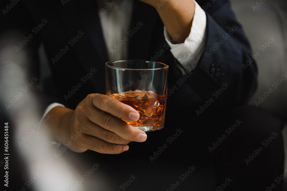 Young man holding whiskey glass in bar or restaurant.