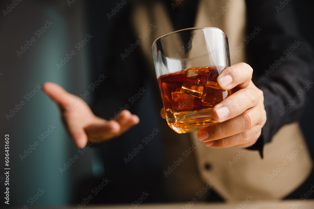Young man holding whiskey glass in bar or restaurant.