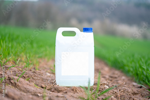 white plastic container with agricultural chemicals or fertilizers on a green field