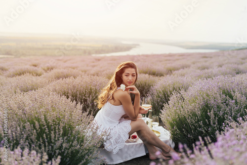 Fototapeta Naklejka Na Ścianę i Meble -  Calm and relaxed woman is sitting on the lavender field with beautiful landscape on background. She enjoying beautiful moment.