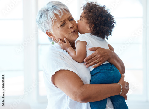 Love, kiss and grandmother with child in a living room for bonding, hug and playing in their home. Kissing, family and senior female enjoying retirement with grandchild, babysitting and hugging