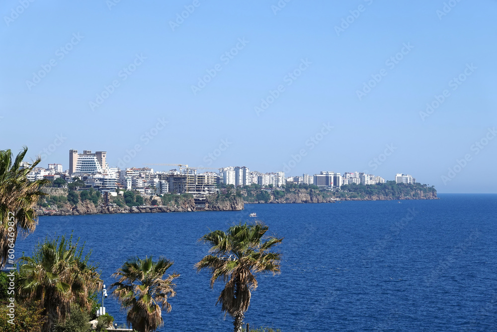 View to the water area and the port of Antalya with boats and yachts in the sea near the old city from park with palms in sunny day