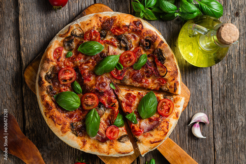 Appetizing pizza. Pizza with ham, mushrooms and tomatoes on a wooden background