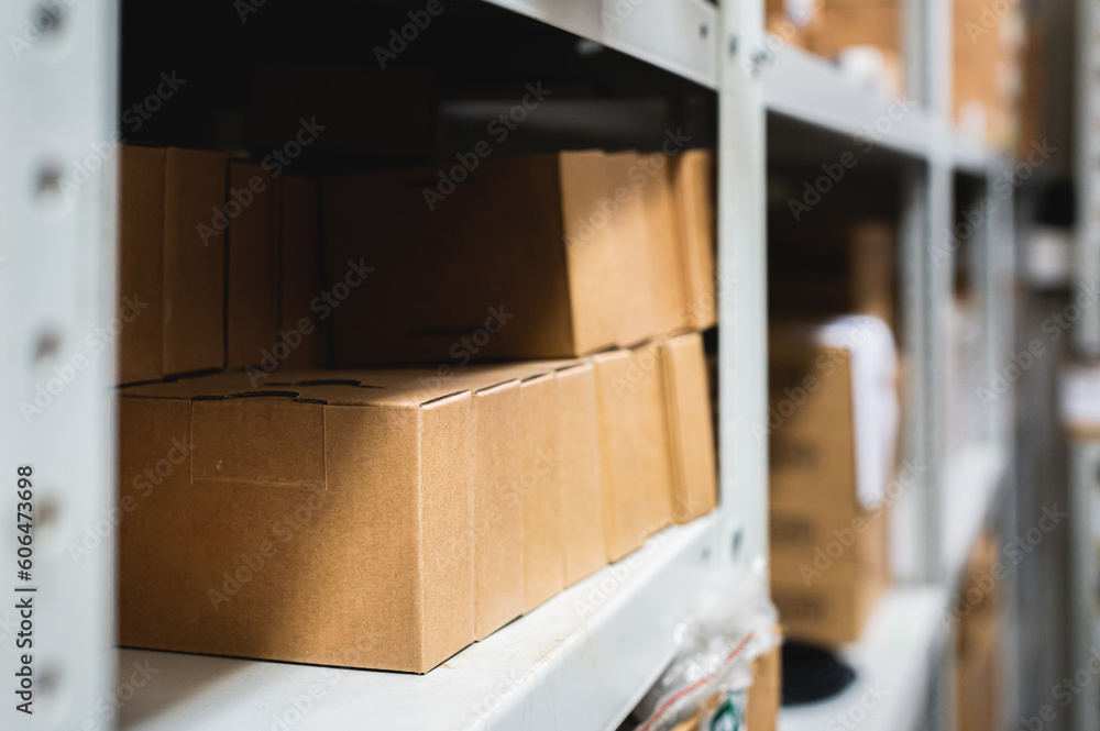 Rows of shelves with cardboard boxes in a modern warehouse, close-up. Brown boxes on metal shelving, side view, background blurred