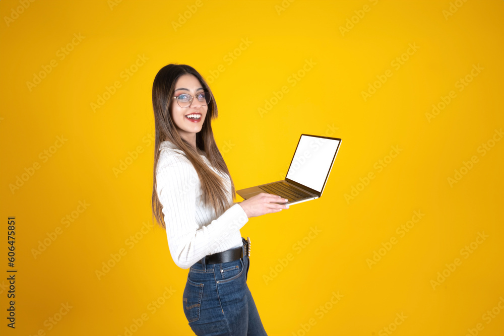 Holding modern laptop, side view portrait of caucasian woman holding modern laptop. Isolated yellow background, copy space. White empty screen notebook mockup. Office worker looking camera, smiling. Holding modern laptop, side view portrait of caucasian woman holding modern laptop. Isolated yellow background, copy space. White empty screen notebook mockup. Office worker looking camera, smiling.