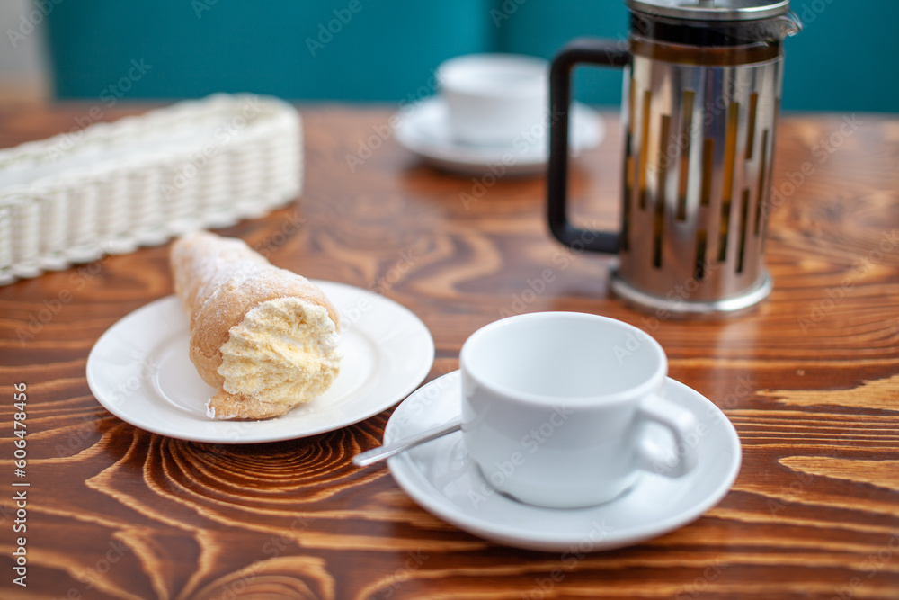 Fresh pastries with filling on the table next to white mugs for coffee or tea for breakfast. Cake for a sweet dessert after lunch at a cozy coffee shop.