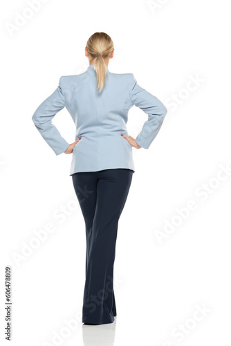 Middle aged senior woman  wearing blue jacket and black trousers on a white background. Rear, back view. © vladimirfloyd