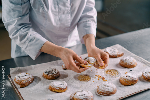 beautiful woman baker tears ready freshly baked hot aromatic buns and checks dough bakery production