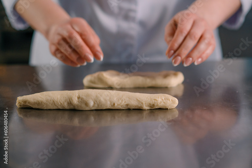 baker forms a braid from raw dough in the kitchen professional kitchen bakery production of pastries