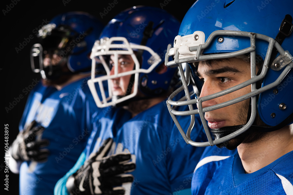 Portrait of three men in blue uniforms for American football with a hand on his chest on a black background. Portrait of three men in blue uniforms for American football with a hand on his chest on a black background.