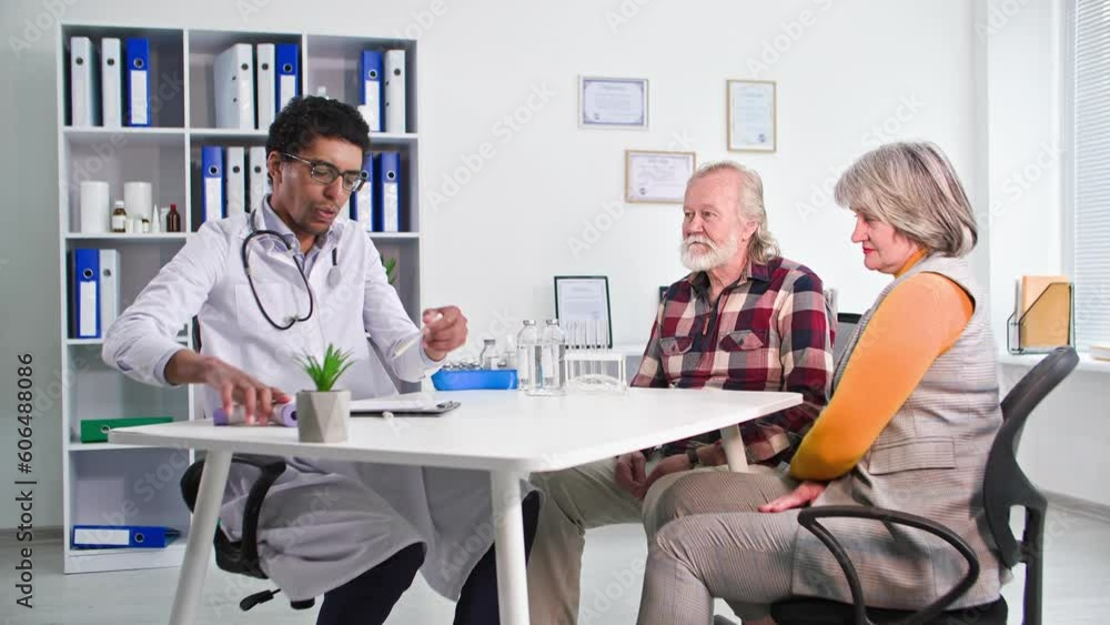 patient reception, afro american male doctor examines an elderly couple in medical office patient reception, afro american male doctor examines an elderly couple in medical office