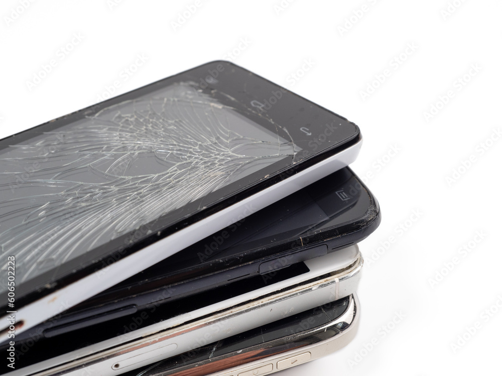 Damaged mobile phones. A bunch of broken smartphones. Used phones on a light background. Damaged mobile phones. A bunch of broken smartphones. Used phones on a light background.