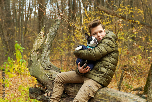 A teenager hugs his dog while sitting in the park. Favorite pets.