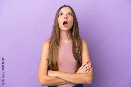 Young Lithuanian woman isolated on purple background looking up and with surprised expression