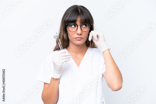 Dentist caucasian woman holding tools isolated on white background having doubts and thinking © luismolinero