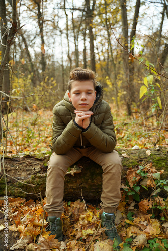 A fashionable teenager sits in the woods and meditates. Adolescent mental health.