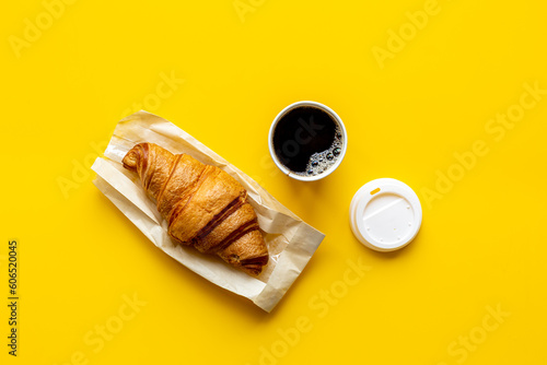 One disposible paper cup of coffee to go with croissant photo