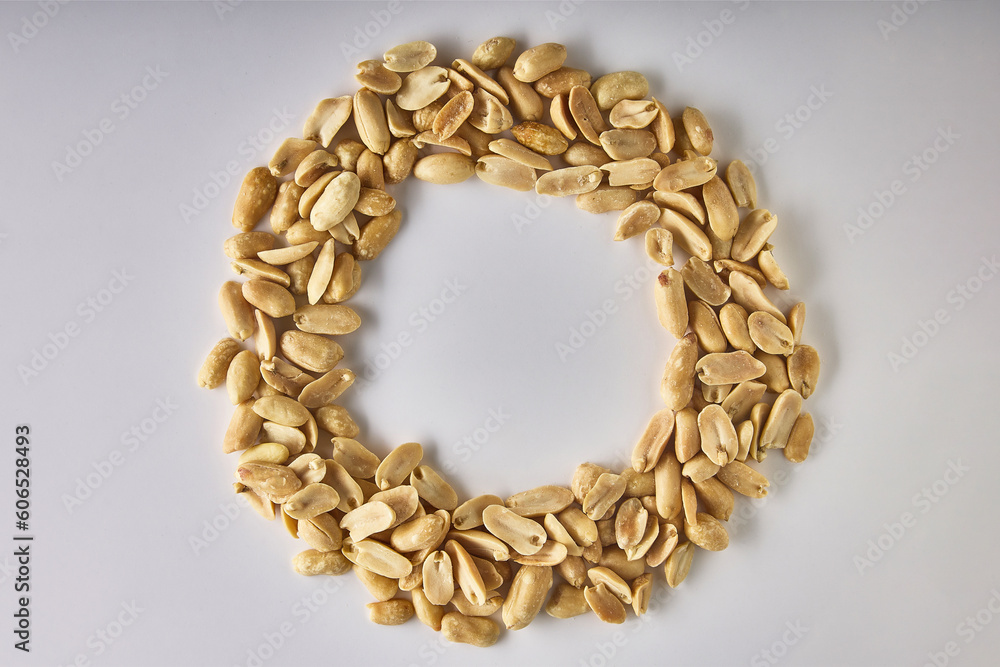 Delicious, healthy dried peanuts are laid out in a circle in the form of a letter on a white background for advertising. Visual design of the banner for advertising healthy nuts for vegetarians