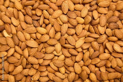 Background of brown large raw peeled almonds, arranged arbitrarily. A lot of delicious healthy almonds laid out in front of the camera, top view