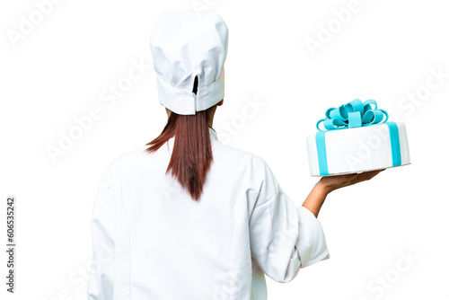 Woman pastry chef with a big cake in back position