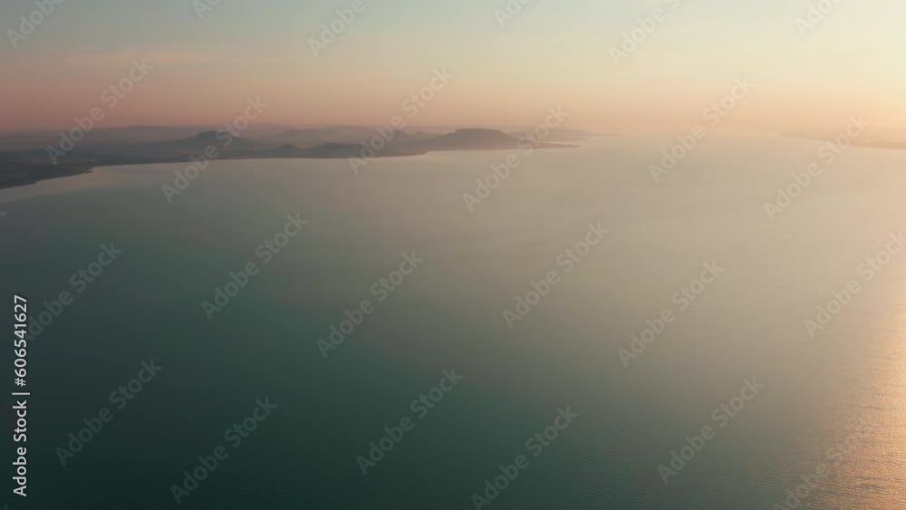 Drone View of Calm Waterscape nad Sunset above Lake Balaton in Hungary, Central Europe. Panorama of Shore with Sunshine on Surface with grean Areas in background. 4k drone shot Drone View of Calm Waterscape nad Sunset above Lake Balaton in Hungary, Central Europe. Panorama of Shore with Sunshine on Surface with grean Areas in background. 4k drone shot
