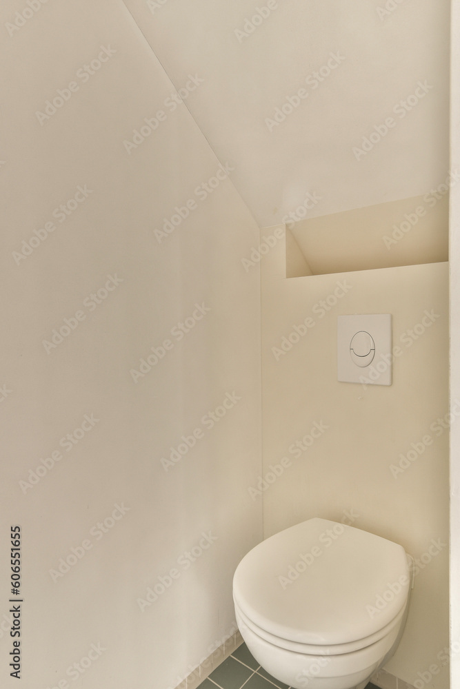 a toilet in the corner of a room with white walls and green tiles on the floor, there is an electrical outlet a toilet in the corner of a room with white walls and green tiles on the floor, there is an electrical outlet