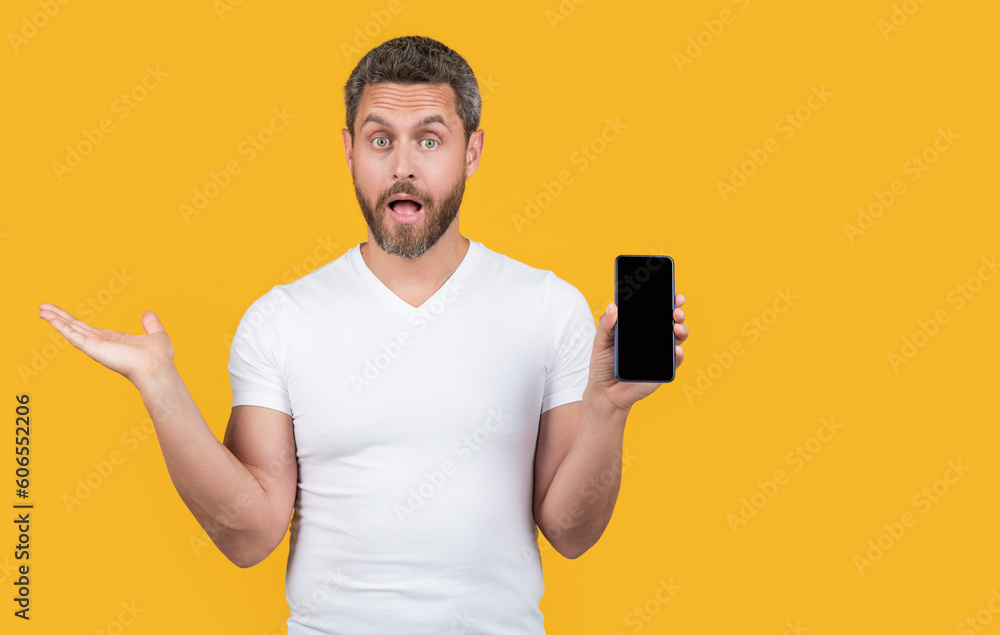 surprised man showing phone screen isolated on yellow background. man showing phone screen surprised man showing phone screen isolated on yellow background. man showing phone screen