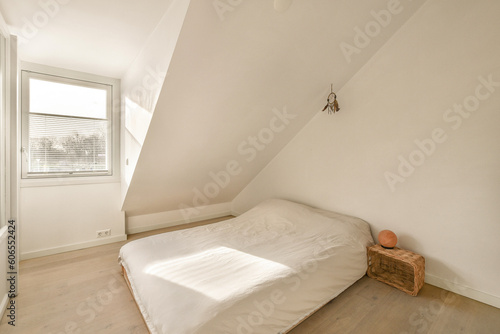a bed in the corner of a room with white walls and wood flooring on the right side of the room