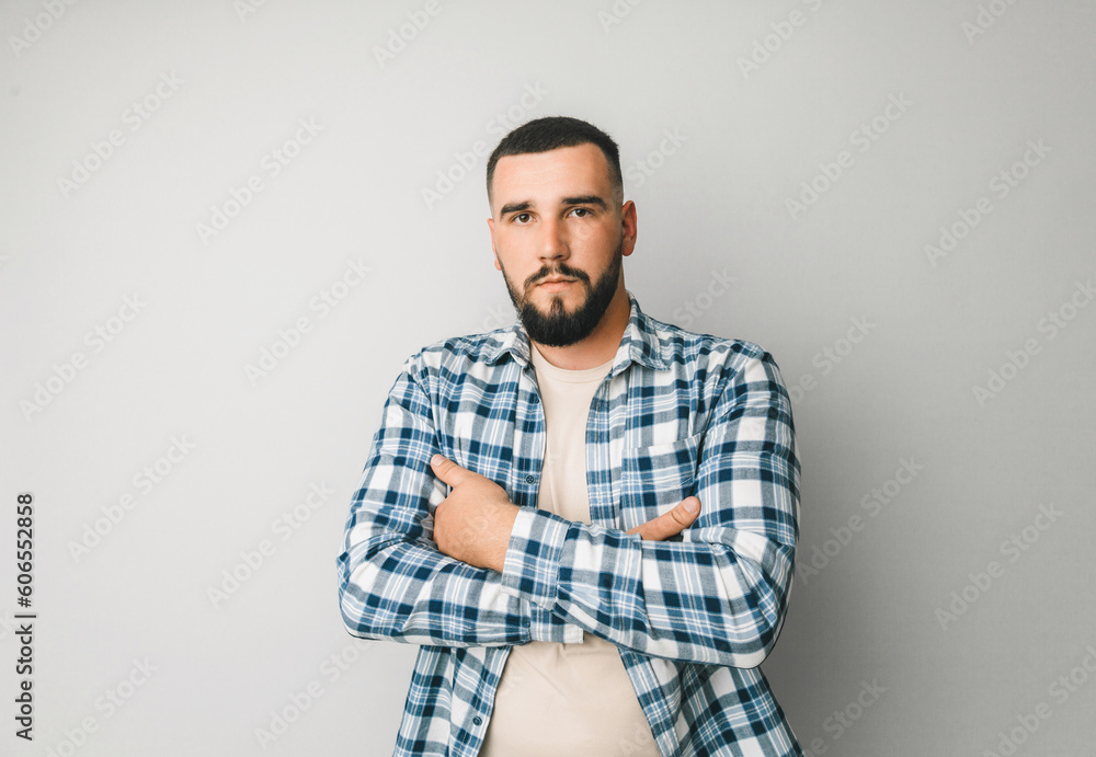 A man in a plaid shirt on a gray background crossed his arms over his chest. portrait of a serious man. A man in a plaid shirt on a gray background crossed his arms over his chest. portrait of a serious man.