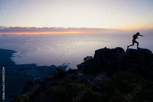 Silhouette of a person in the running in the mountains having climbed to the top of a mountain at sunrise