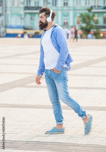 handsome hipster in music earphones outside. hipster in music earphones in the street.