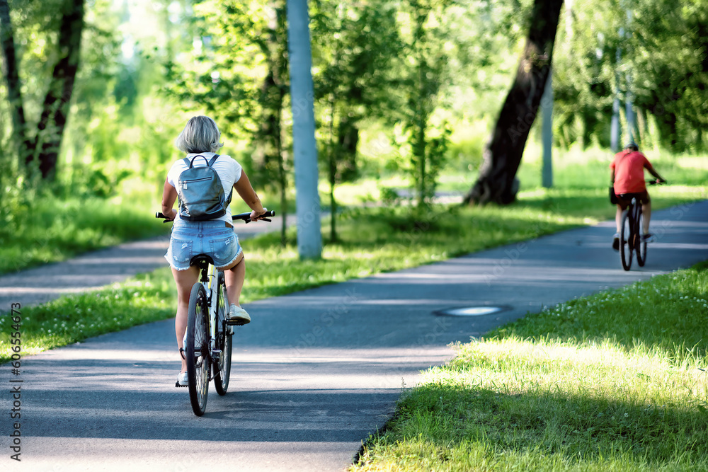 Obraz premium A young woman riding a bicycle in a park in summer in the sunny morning.