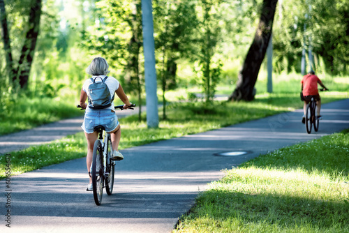 A young woman riding a bicycle in a park in summer in the sunny morning. © Marina