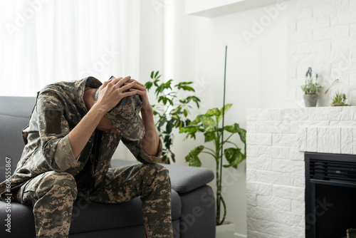 A man in a military uniform is sitting in a chair by the window. Concept: a soldier at a psychologist's appointment, post-traumatic stress syndrome, mental disorder, the consequences of war © Angelov