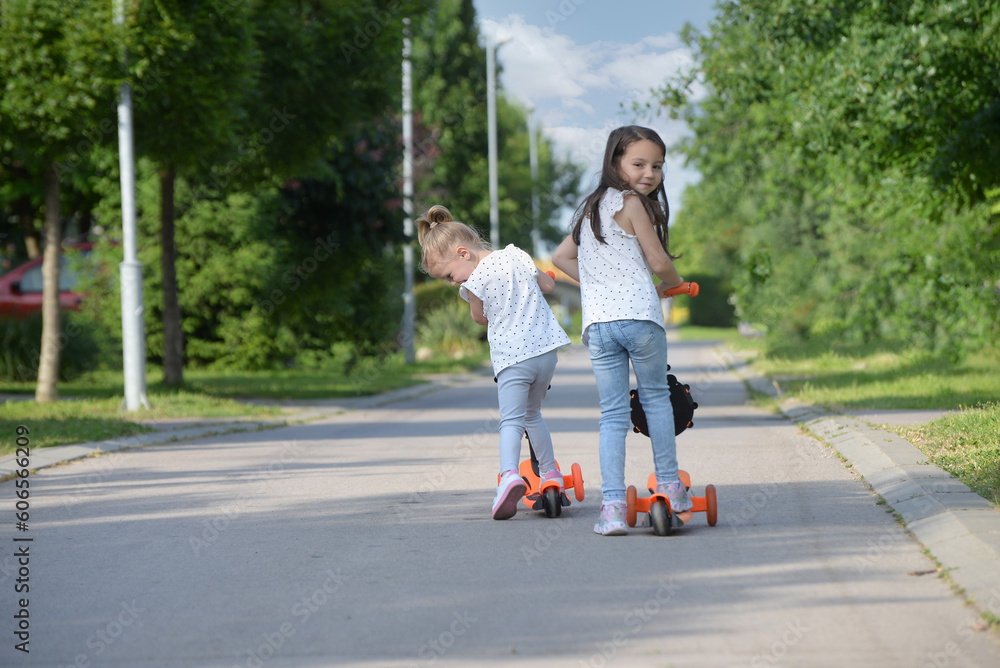 Two little sisters riding their scooters Two little sisters riding their scooters