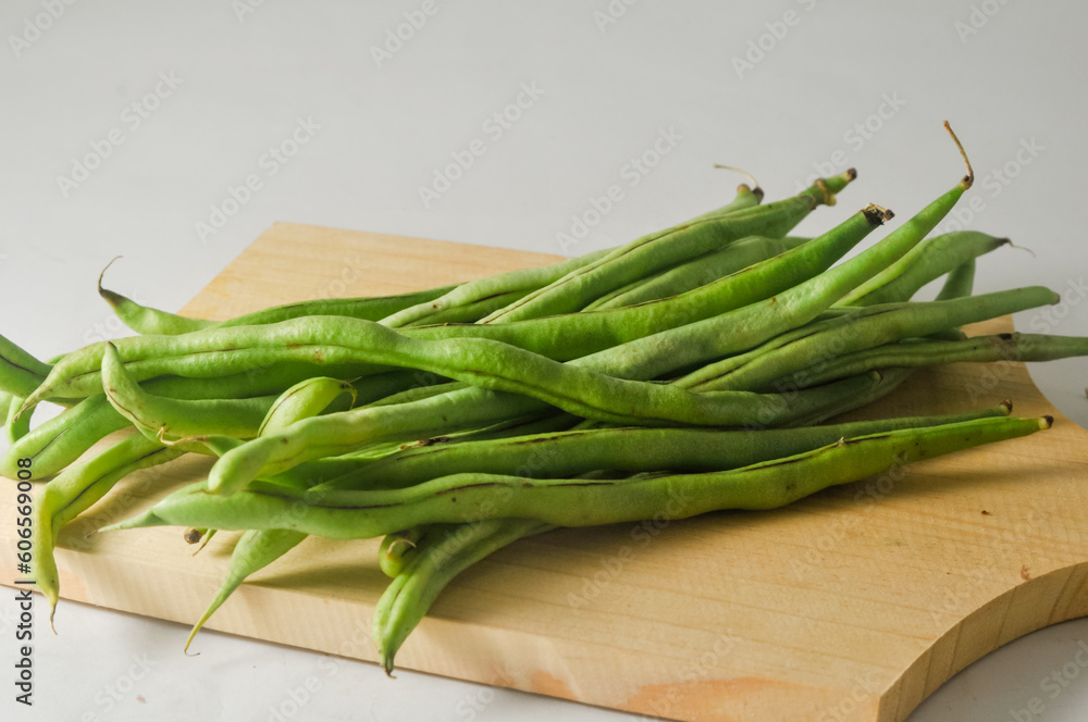 Some green beans on a wooden cutting board isolated on a white background Some green beans on a wooden cutting board isolated on a white background