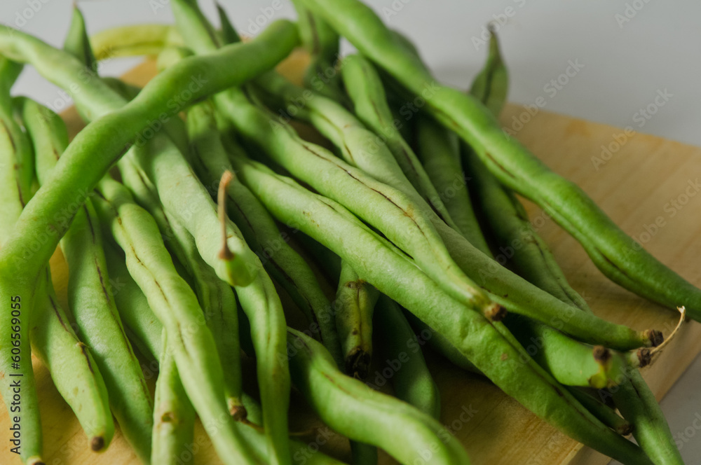 Some green beans on a wooden cutting board isolated on a white background Some green beans on a wooden cutting board isolated on a white background