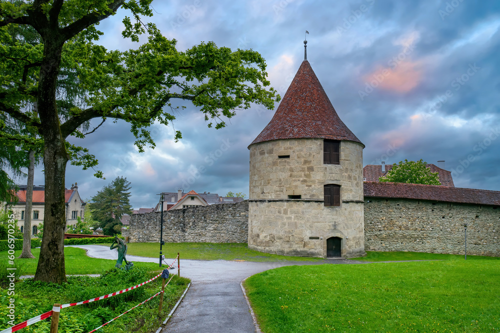 Park view of Huwiler Tower in Zug, Switzerland at rainy spring evening. Huwiler Tower is the smallest of the four outer town wall towers in the city of Zug