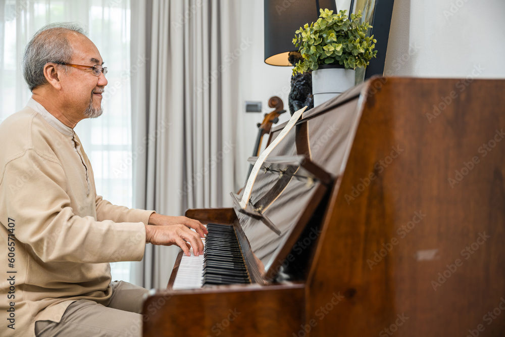 Happy relaxation Asian senior retirement man with eyeglasses learn to play  piano at home, elderly old man playing music on piano in living room,  lifestyle life after retirement, Close up hands Stock