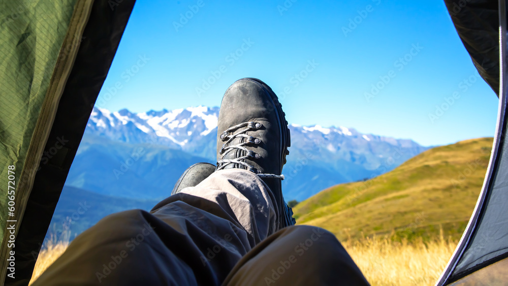 Φωτογραφία leg tourist in boots out of the tent with mountains in the background