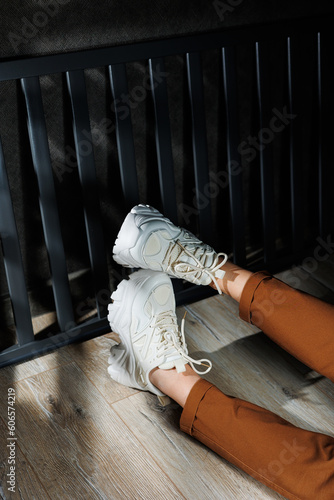 Collection of summer leather sneakers for women. Close-up of female legs in white sneakers. Women's summer sneakers with laces.