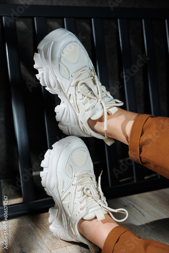 Collection of summer leather sneakers for women. Close-up of female legs in white sneakers. Women's summer sneakers with laces.