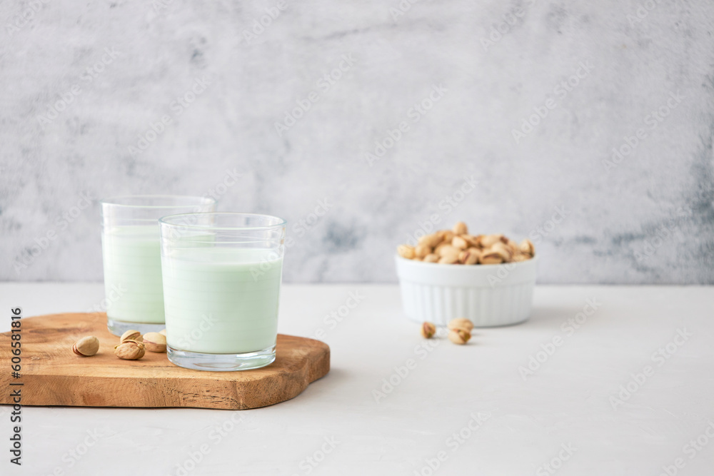 Glasses of homemade pistachio milk on a wooden board next to pistachios. The perfect drink for vegans Glasses of homemade pistachio milk on a wooden board next to pistachios. The perfect drink for vegans