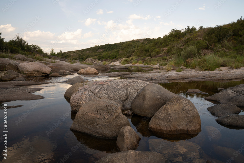 View of the river across the rocky hills at sunset. The sky reflection in the water surface.