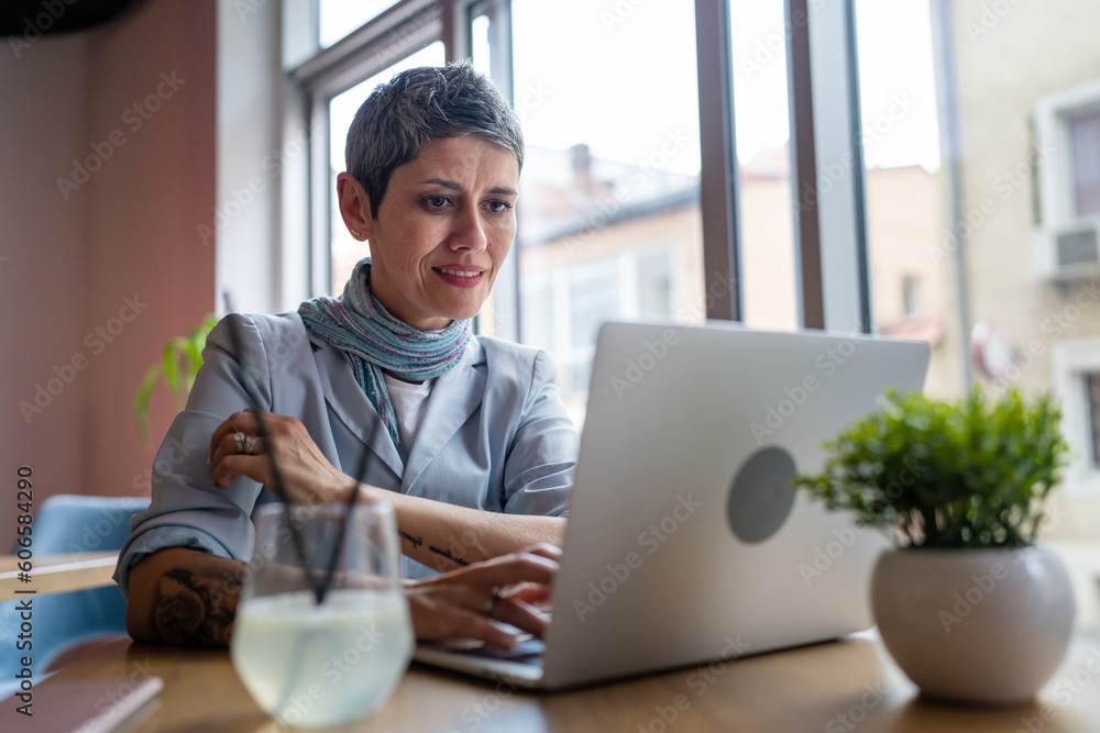 One woman mature adult senior female work on laptop at cafe One woman mature adult senior female work on laptop at cafe