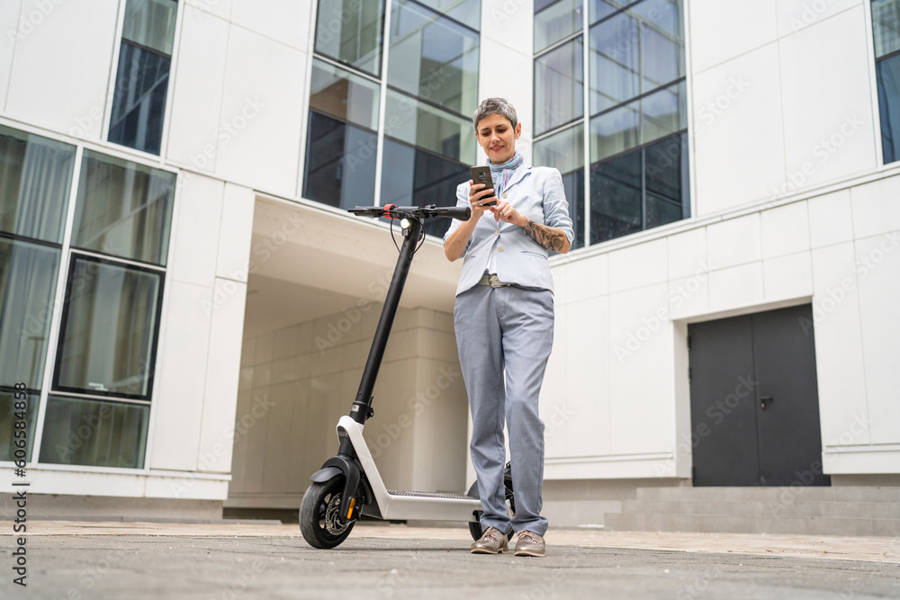 woman mature senior use mobile phone stand by electric kick scooter woman mature senior use mobile phone stand by electric kick scooter