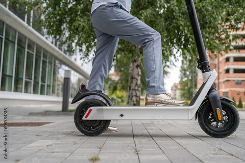 Feet of unknown woman stand or drive electric kick scooter e-scooter