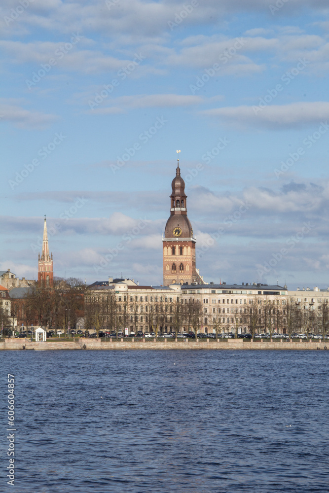Obraz premium Beautiful view of the tower of the Dome Cathedral on the banks of the Daugava River in Riga, Latvia on a sunny day