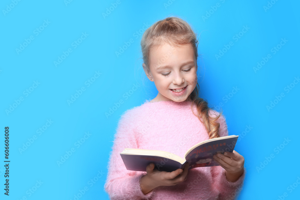Happy little girl reading book on light blue background. Space for text Happy little girl reading book on light blue background. Space for text